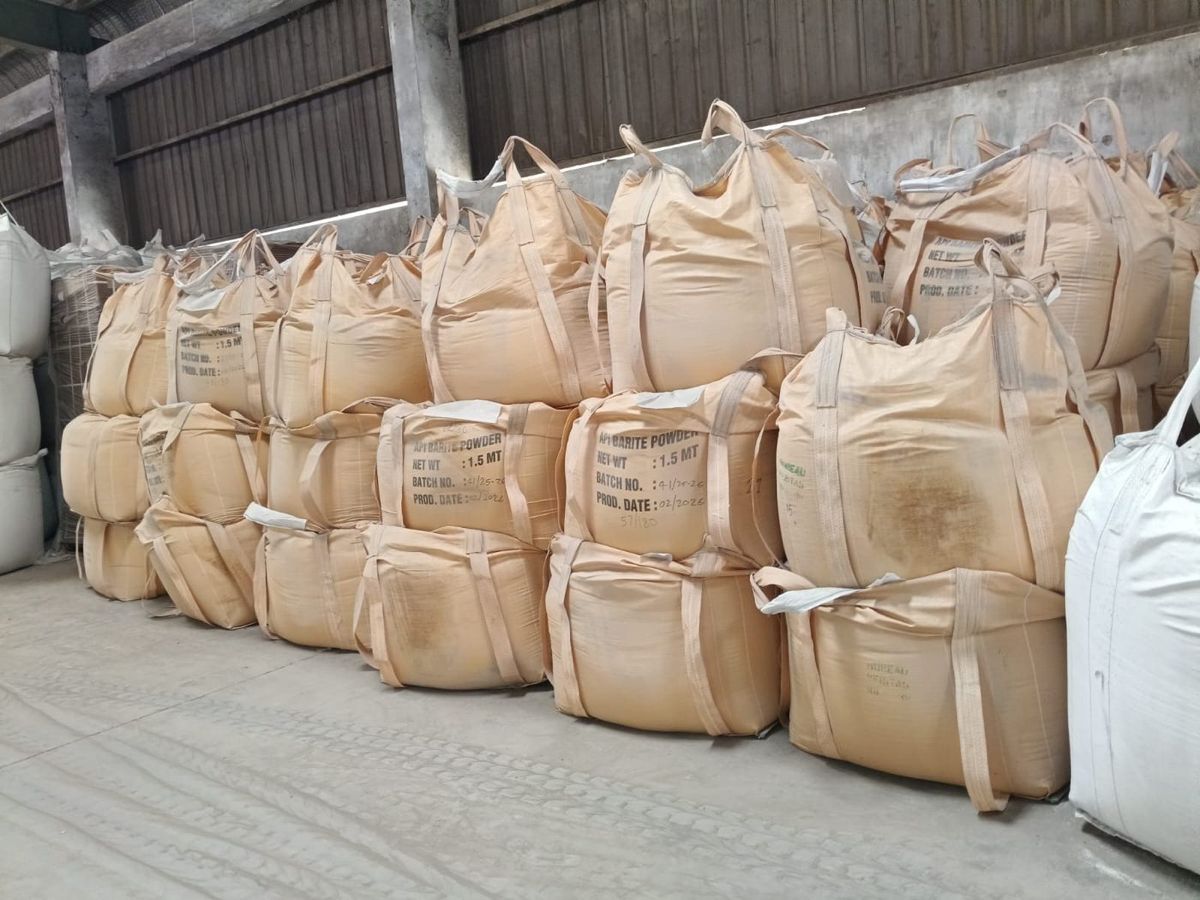 Stacked jumbo bags of barite powder, each printed with net weight 1.5 MT and a hand-filled batch number and production date.