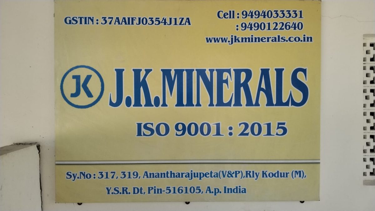 The yellow J.K. Minerals signboard on a white wall: the JK mark, ISO 9001:2015, GSTIN 37AAIFJ0354J1ZA, two mobile numbers, www.jkminerals.co.in, and the address Sy. No. 317, 319, Anantharajupeta (V&P), Rly. Kodur (M), Y.S.R. District, Pin 516105, Andhra Pradesh.