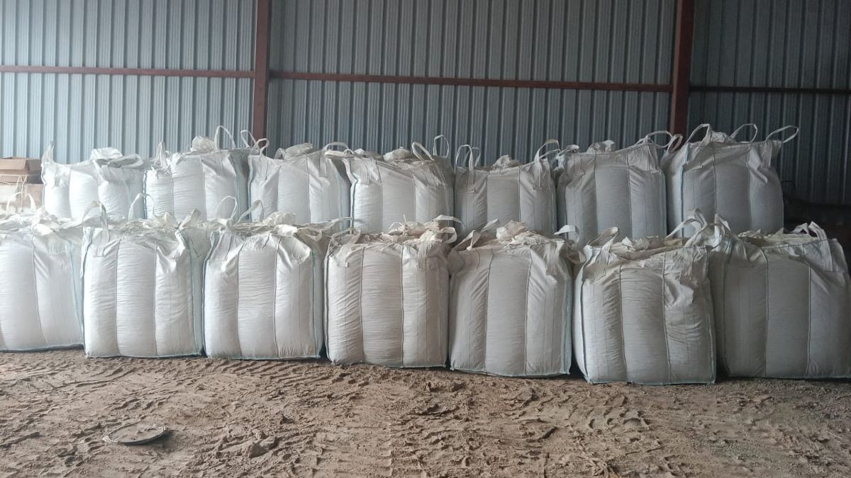 Around thirty filled jumbo bags standing in rows inside a covered shed.